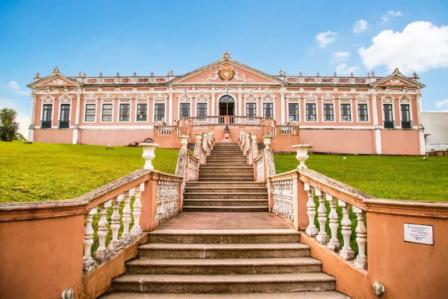 Fachada da Sociedade Portuguesa de Bagé com escadaria central e arquitetura clássica preservada, em foto atual do prédio histórico.