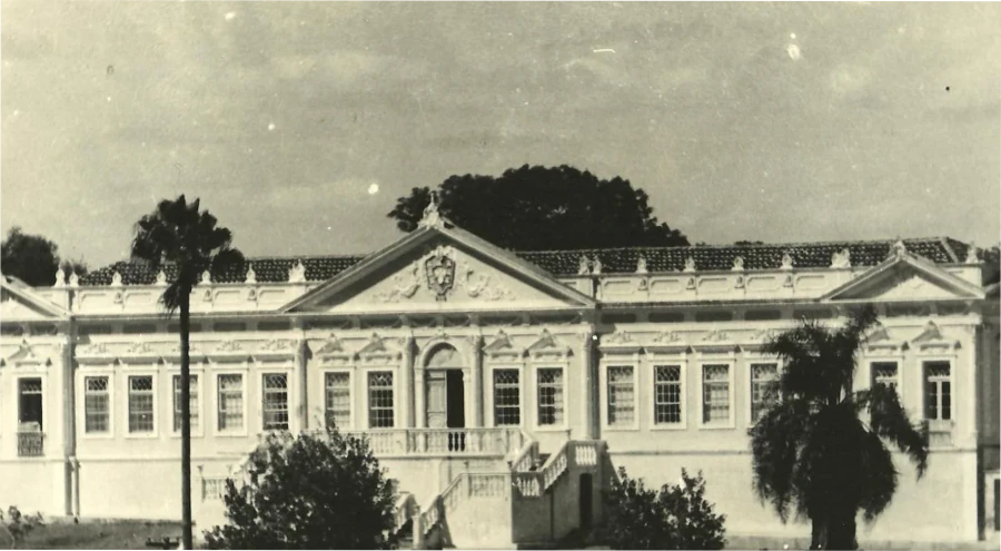 Imagem antiga em preto e branco da Sociedade Portuguesa de Bagé com destaque para a fachada histórica e detalhes arquitetônicos clássicos.